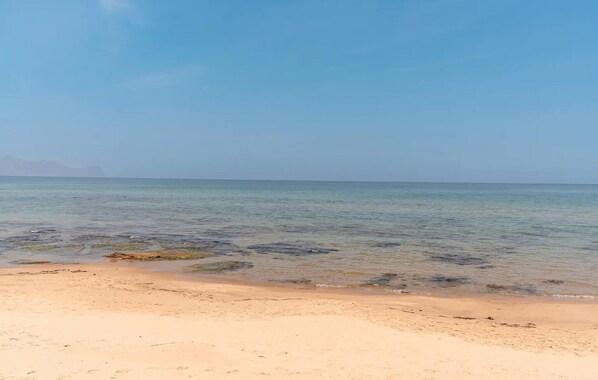 Ein Strand mit klarem Wasser und sandigem Ufer.