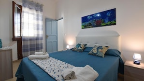 Un dormitori amb un llit, un quadre, una porta i una finestra amb cortines.