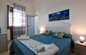 Ein Schlafzimmer mit Bett, Gemälde, Tür und einem Fenster mit Vorhängen.