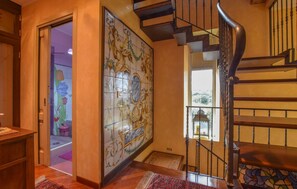 Un escalier avec une rampe en bois et un mur recouvert de carreaux aux motifs floraux.