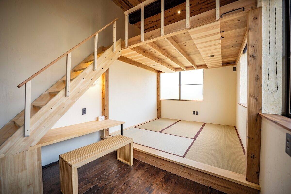 A traditional Japanese room with tatami flooring, a wooden staircase, and a small bench.