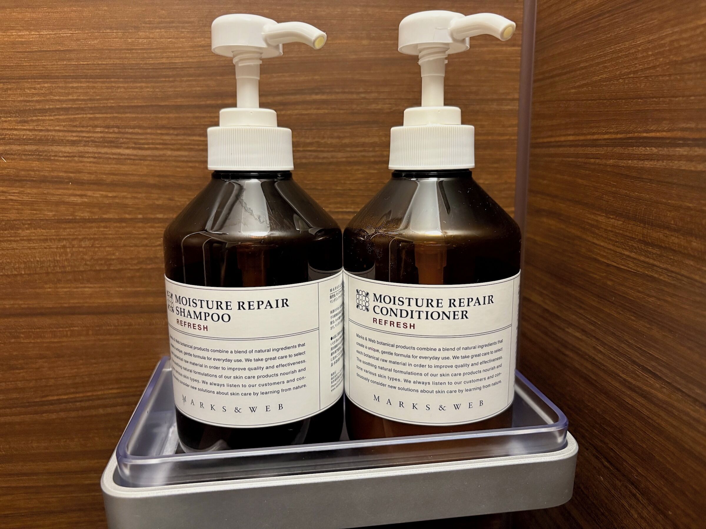 Two bottles of Moisture Repair Shampoo and Conditioner on a metal tray.