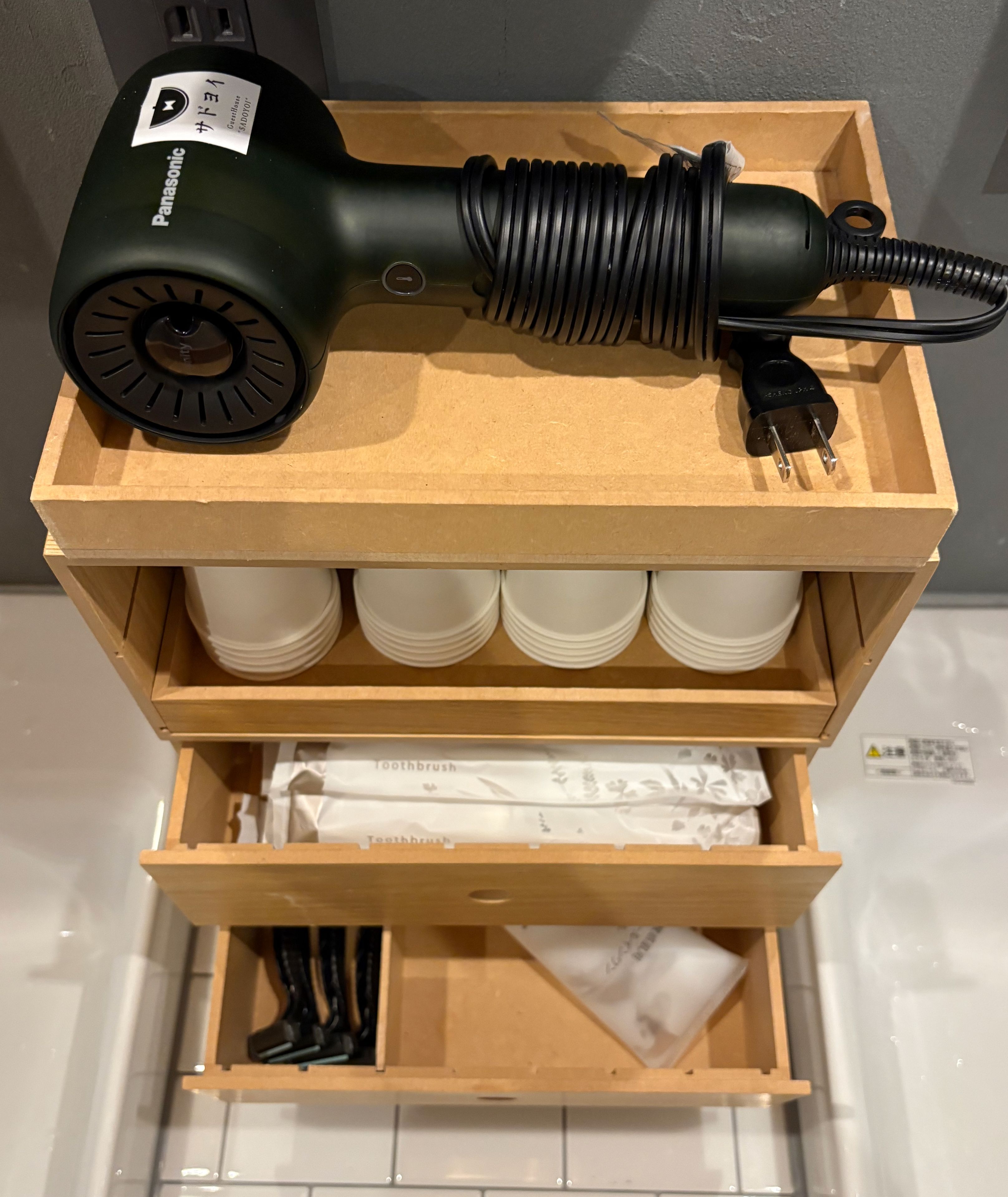 Eine Aufbewahrungsbox mit einem Föhn, Tassen und einer Zahnbürste.