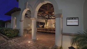 Eine Bar und ein Grillrestaurant namens 'Blossoms' mit einer Terrasse, die einen Ziegelboden und weiße Säulen aufweist.