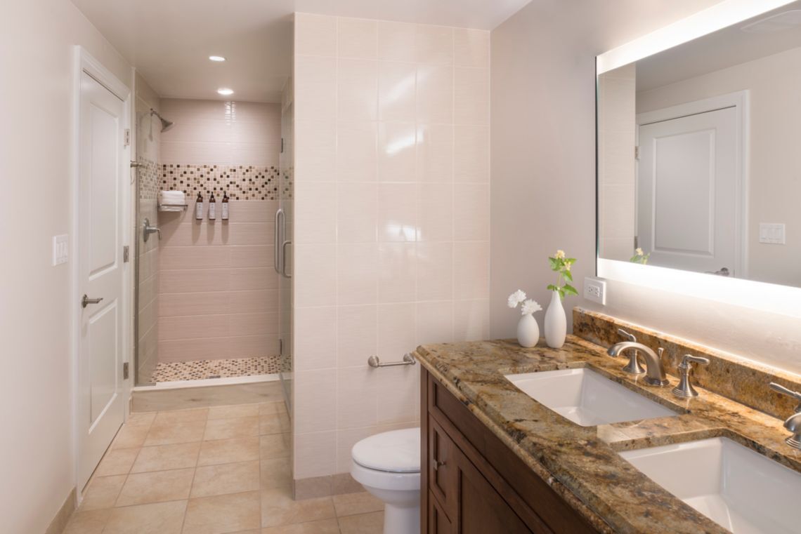 Une salle de bain moderne équipée d’une douche, de toilettes et de deux lavabos avec un plan de travail en marbre.