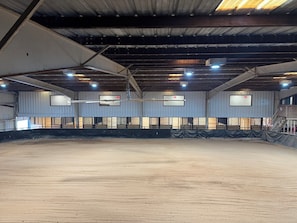 Una cancha deportiva interior con techo alto, vigas metálicas y varias luces.