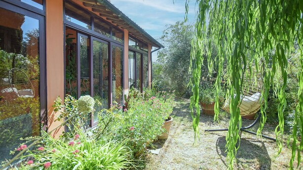 Een modern huis met grote glasramen, een tuin met diverse planten en een hangplant.