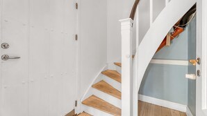 Een witte deur met een messing handvat, een houten trap met witte leuningen en een blauwe muur.