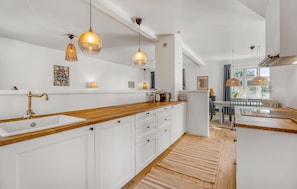 Een moderne keuken met witte kasten, houten aanrecht en hanglampen.