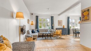 Een moderne woonkamer met een bank, een bijzettafeltje en een eethoek met een stoel.