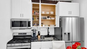 A modern kitchen with white cabinetry, stainless steel appliances, and a built-in microwave. - Luxury 4BR Sleeps 16 • Free Parking • Walk to Train • Near NYC (Yonkers)