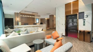 Eine moderne Hotelhalle mit Rezeption, Sitzgelegenheiten und einem Aufzug.