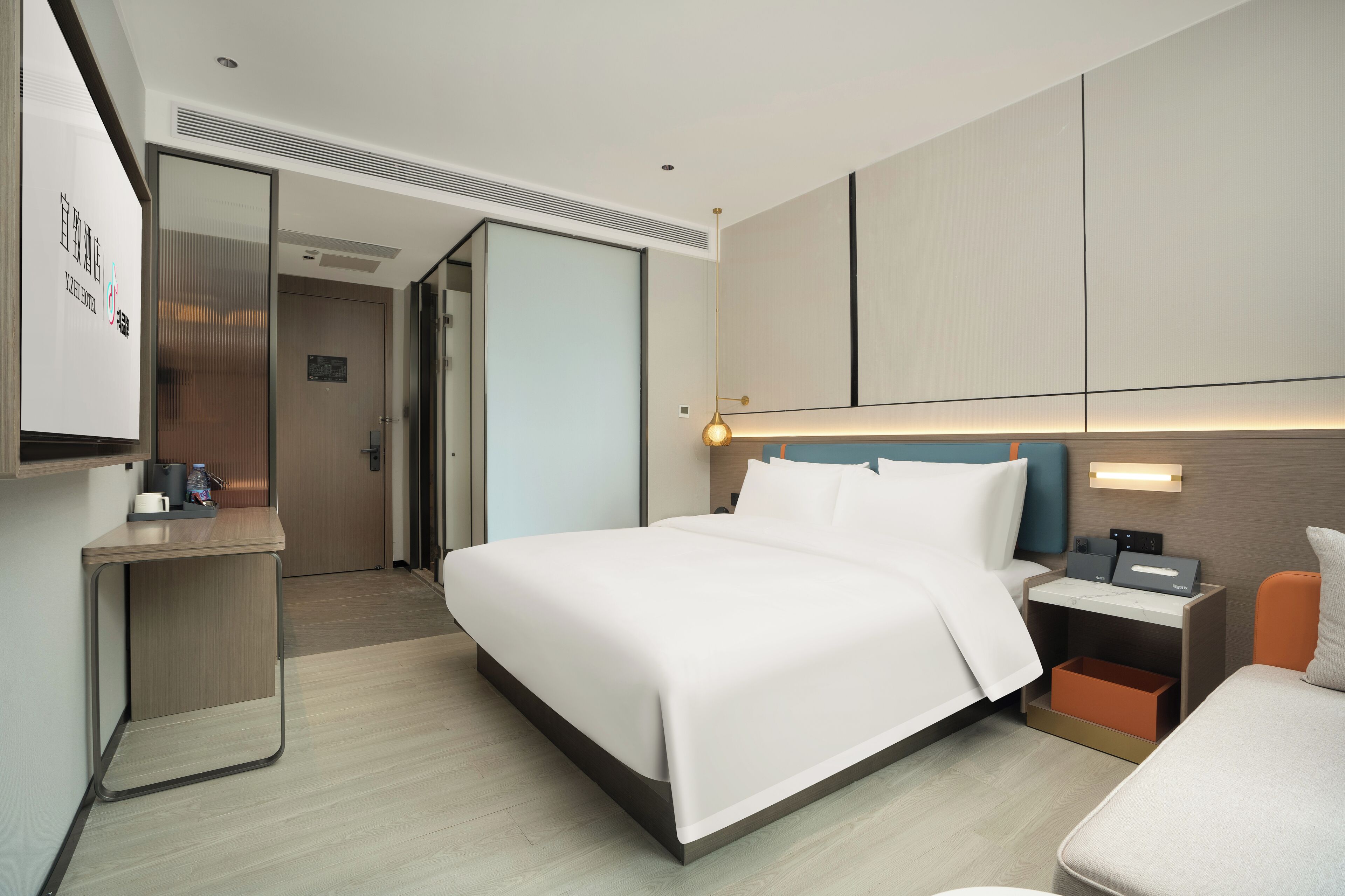 Una habitación de hotel moderna con una cama grande, mesitas de noche, un escritorio y un espejo.