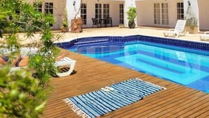 A two-story building with a swimming pool, outdoor seating, and a wooden deck. - La Marina Resort (Buzios)