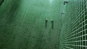 A shower area with green tiled walls and a curved floor. - La Marina Resort (Buzios)