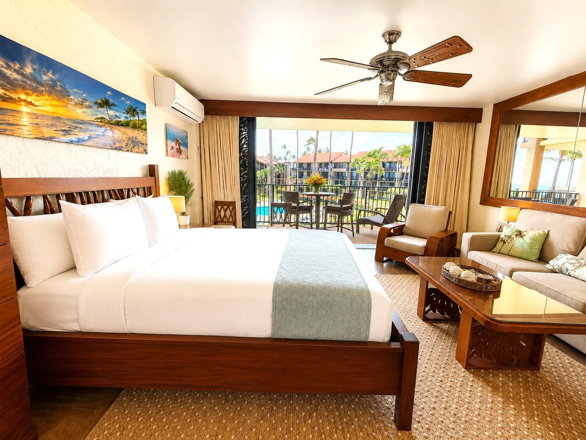 A hotel room with a bed, a sofa, a coffee table, and a balcony with a view of the pool and buildings.