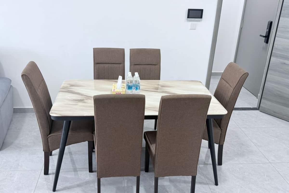 A conference room with a marble table, six brown chairs, and a small table with water bottles.