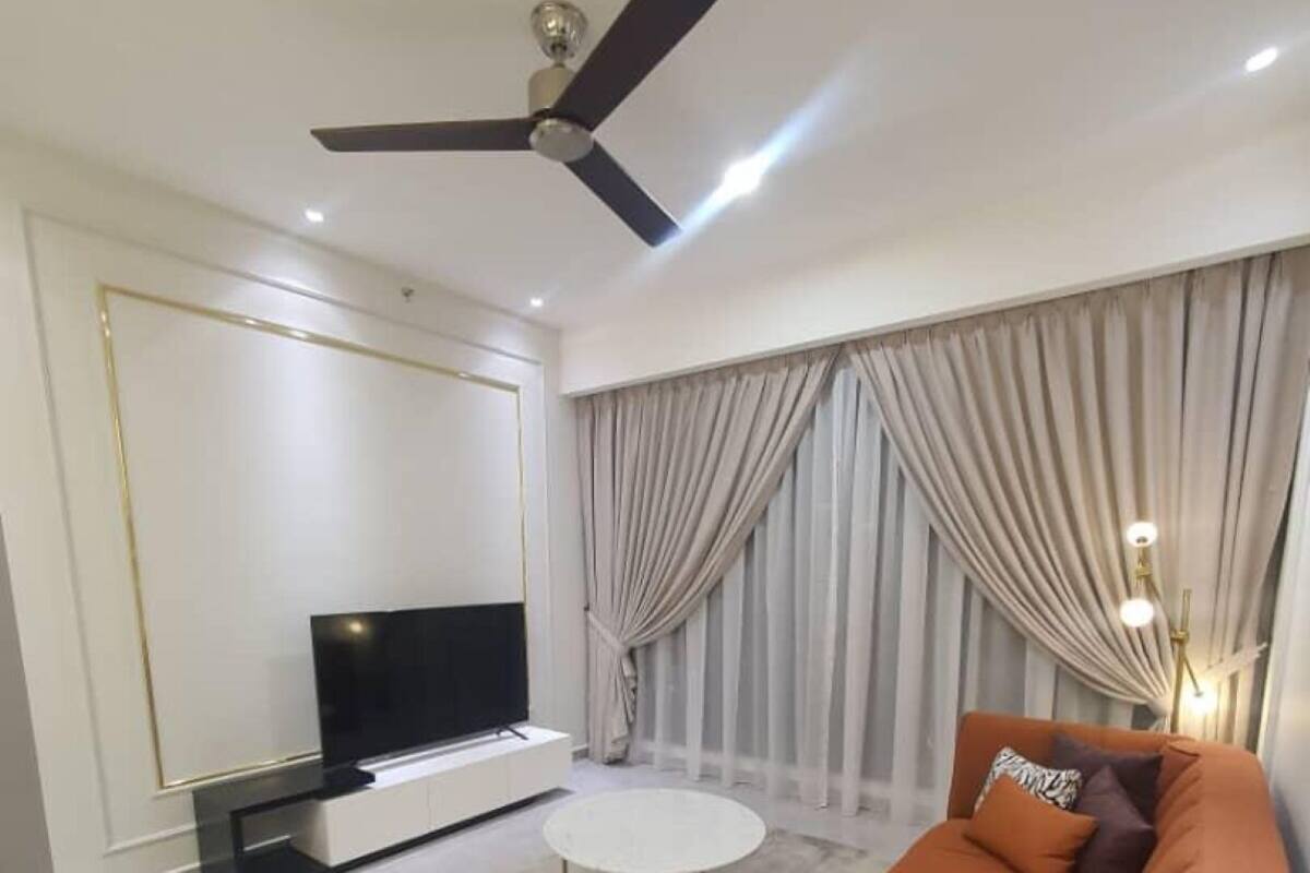 A modern living room with a flat-screen TV, a round coffee table, a sofa, and a ceiling fan.