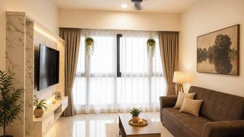 A modern living room with a flat-screen TV, a sofa, a coffee table, and a ceiling fan.