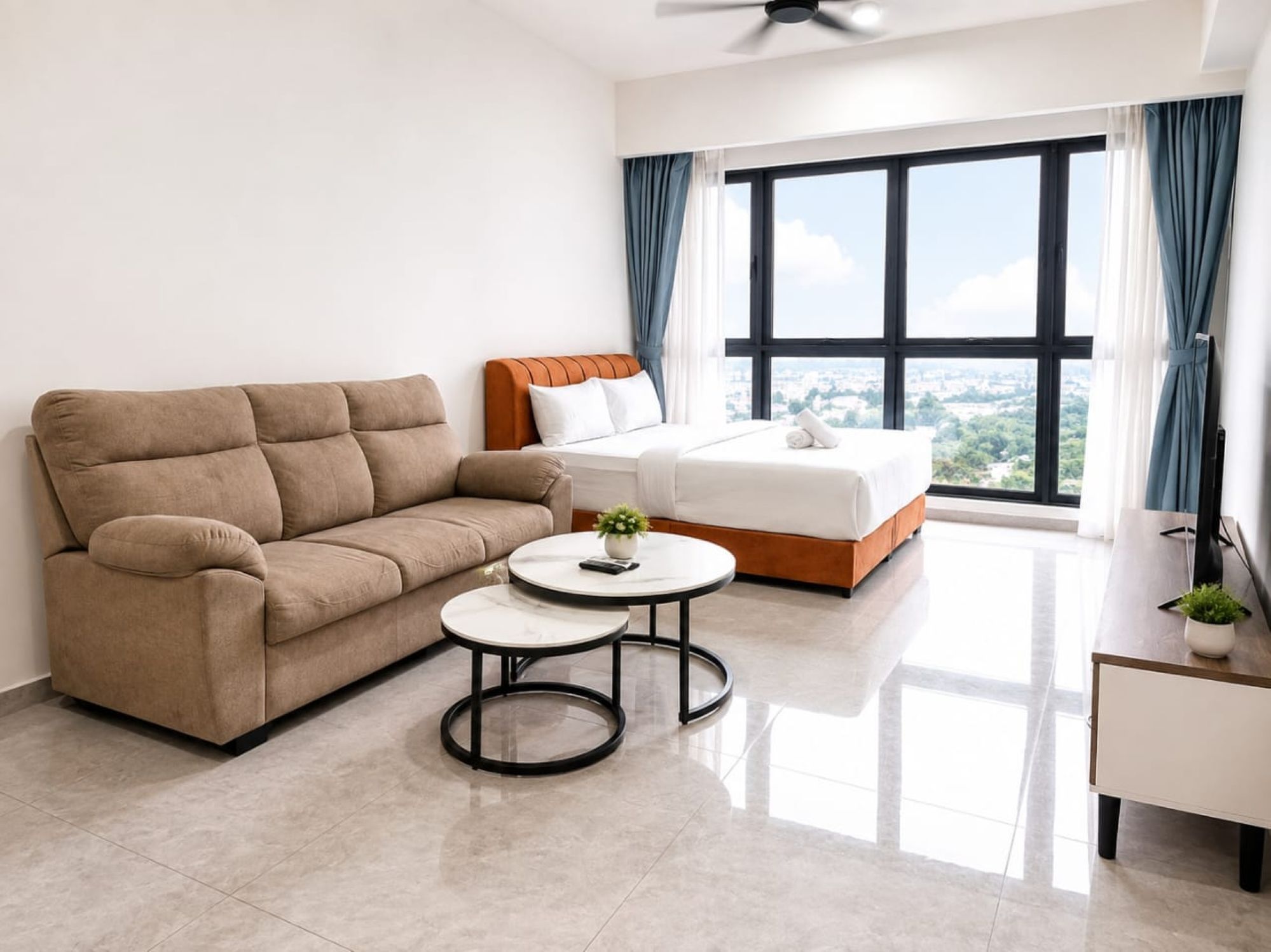 A modern hotel room with a sofa, a bed, a small round table, and a large window with curtains.