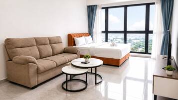A modern hotel room with a sofa, a bed, a small round table, and a large window with curtains.