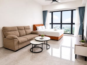 A modern hotel room with a sofa, a bed, a small round table, and a large window with curtains. - The Trusted Hospitality At Agile Suites (Kuala Lumpur)