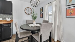 A dining area with a round table, chairs, a clock, and framed pictures on the wall. - Beautiful Meandering Way Retreat (Fort Smith)