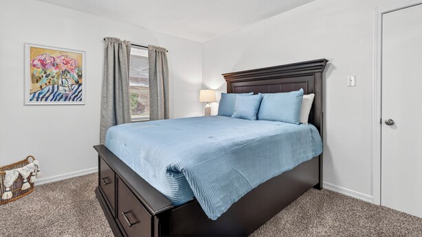 A bedroom with a bed, a nightstand, a lamp, a painting, and a door. - Beautiful Meandering Way Retreat (Fort Smith)