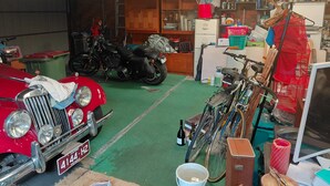 A cluttered garage with a vintage car, a motorcycle, and various tools and items. - Close to beaches, shops with Mikbar 50m towards Springs Beach (Point Lonsdale)