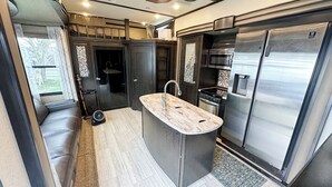 Una cocina compacta con refrigerador, estufa y microondas integrados.
