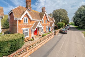 A traditional brick house with a red door, a front porch, and a driveway with parked cars. - Daphne Cottage, Orford, Suffolk (Orford)
