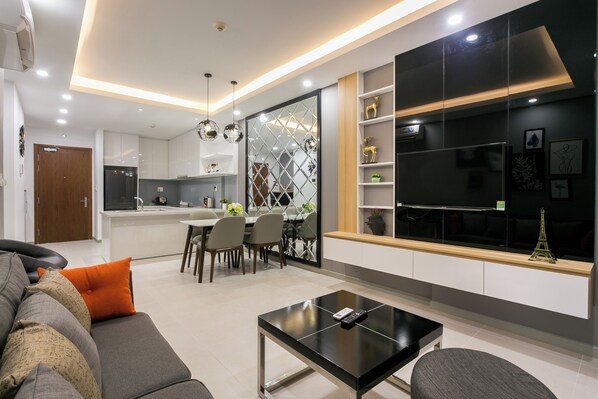 A modern living room with a sofa, a coffee table, and a dining area with chairs and a table. - RiverGate Saigon (Khanh Hoi)