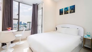 A hotel room with a large bed, a desk, two chairs, a window with curtains, and a city view. - RiverGate Saigon (Ho Chi Minh City)