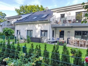 En toetages bolig med balkon, hegnet have og udendørs møbler.