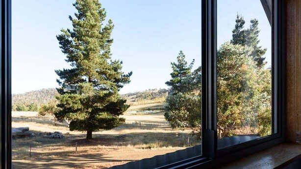 Una ventana con vistas a un paisaje que incluye árboles y un sendero de tierra.
