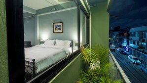Ein Hotelzimmer mit Bett, einem gerahmten Bild an der Wand und Blick auf die Straße.