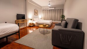 Ein Hotelzimmer mit Bett, einer Couch, einem kleinen Tisch, einem Fernseher und einer Pflanze.