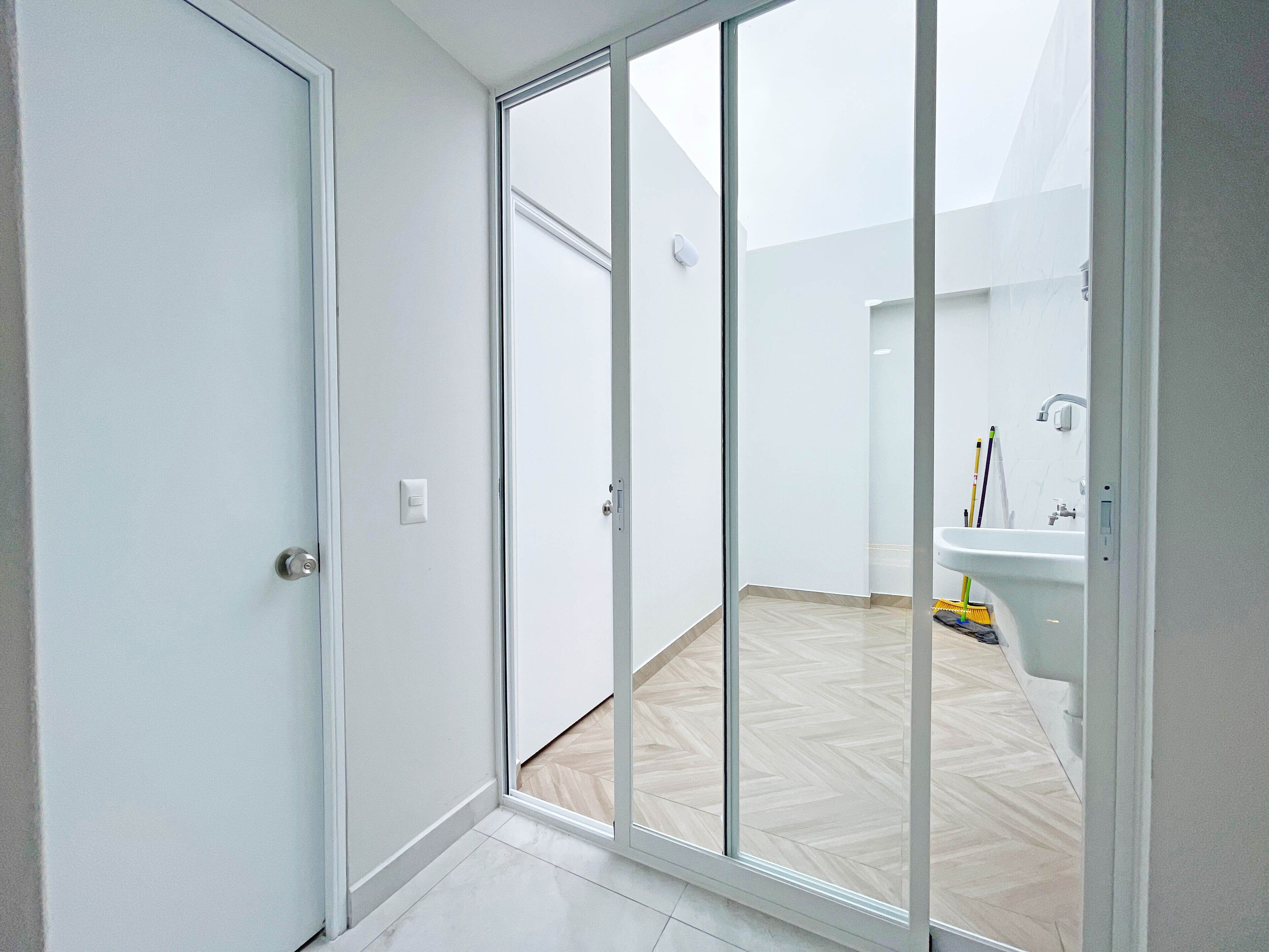 A room with a sliding glass door leading to an outdoor area, a white sink, and a herringbone-patterned floor.