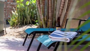 A chair with a folded towel and a bottle, set against a brick wall and bamboo plants.