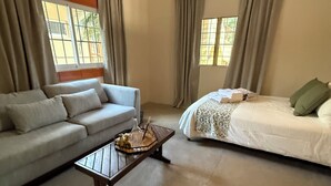 A room with a sofa, a bed, a coffee table, and curtains.