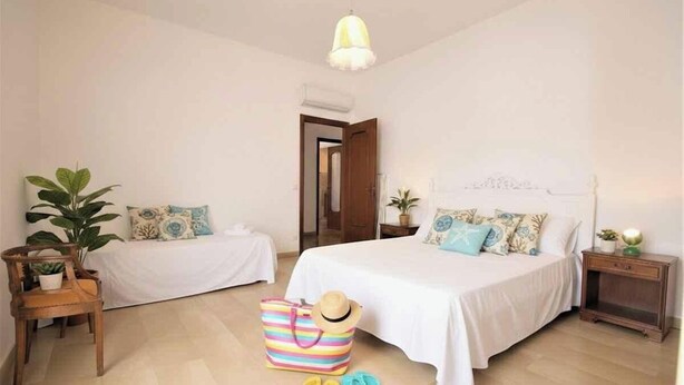 A bedroom with two beds, a wooden nightstand, a chair, a striped bag, and a hat. - Holiday apartment mit Klimaanlage und Balkon (Diano Marina)