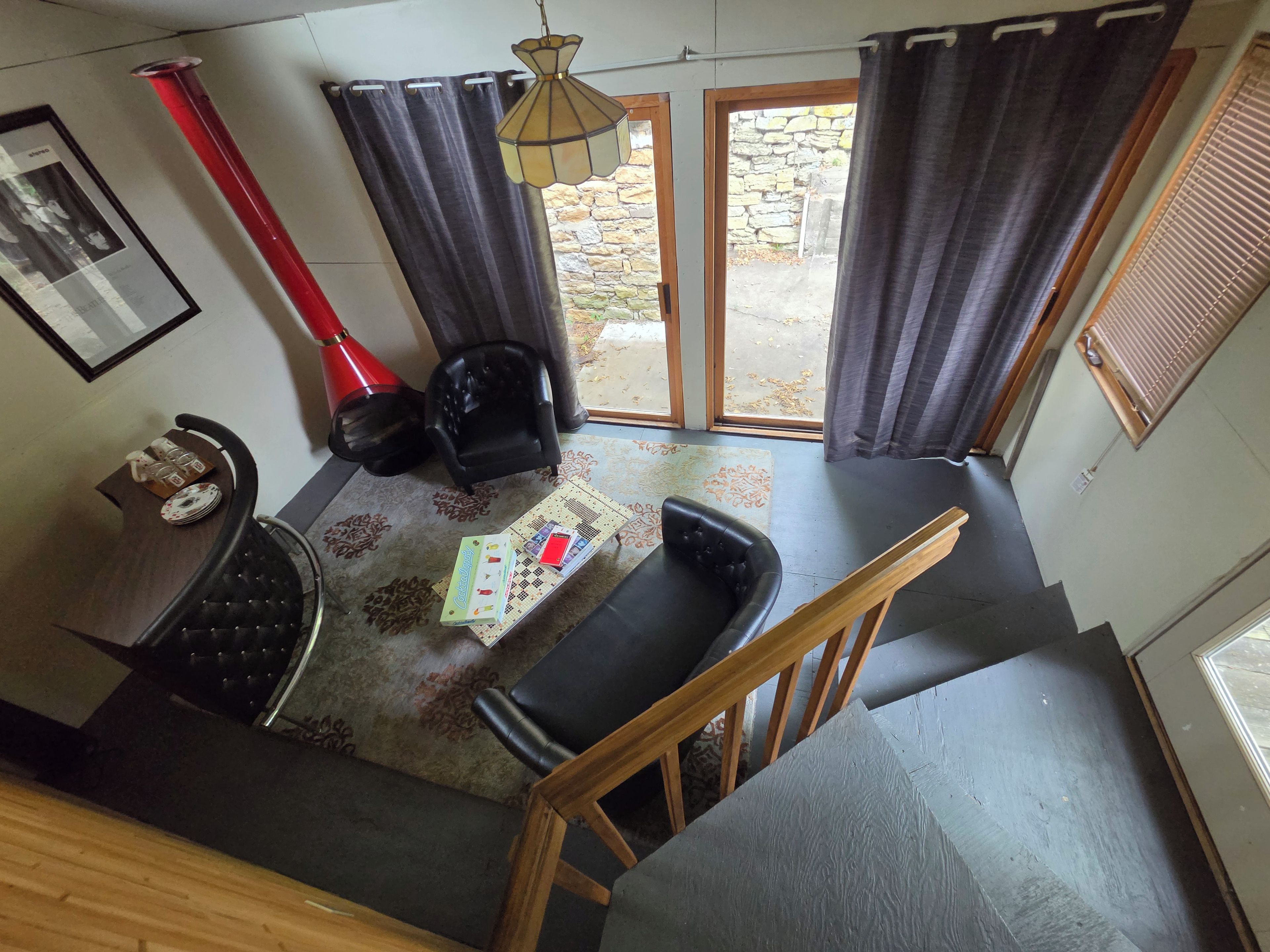 Une pièce comprenant une table à manger, des chaises, un petit canapé, une lampe et donnant sur l’extérieur.