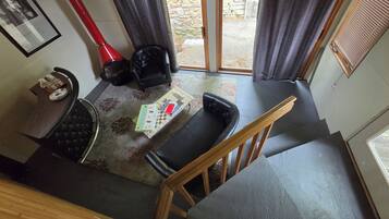 Een kamer met een eettafel, stoelen, een kleine bank, een lamp en uitzicht op het exterieur.