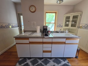 A kitchen with a built-in island, a clock, and a window.