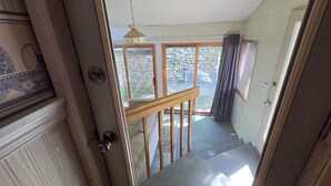 A staircase leading to a balcony with a stone wall and a hanging light fixture. - Mrs. Hippie Inn- Bluffside Suite near the Mississippi River in Alma, Wisconsin (Alma)