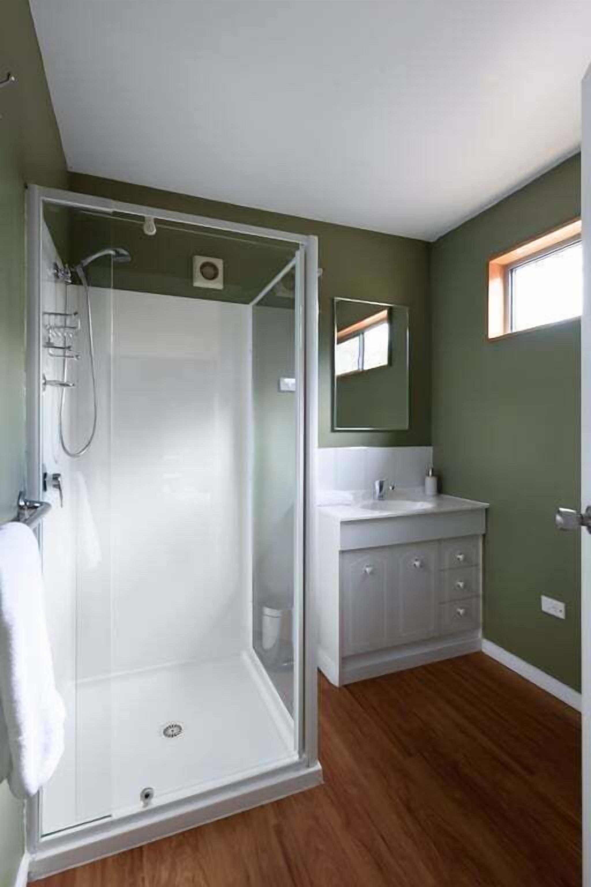 A bathroom with a glass-enclosed shower, a white vanity, and a mirror above it.