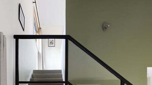 Ein modernes Interieur mit einer Treppe, einem Flachbildfernseher auf einem Holzständer und einer schwarzen Bank.