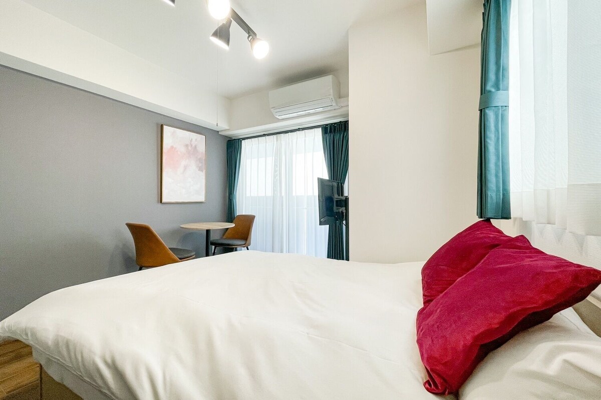A hotel room with a bed, a desk, a chair, and a TV.