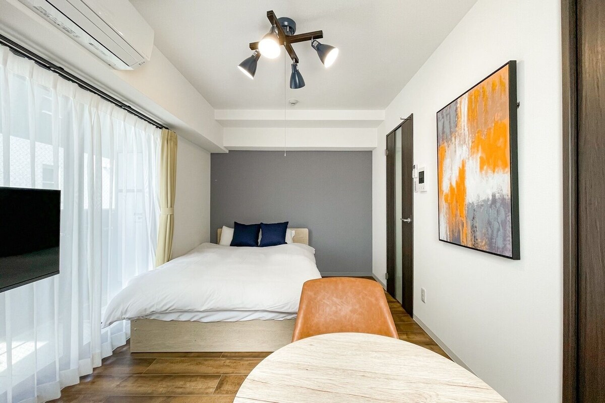 A hotel room with a bed, a TV, a painting, and a chair.
