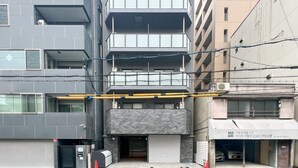 Un edificio de varios pisos con entrada de garage, una puerta de garage cerrada y un letrero visible de un negocio.